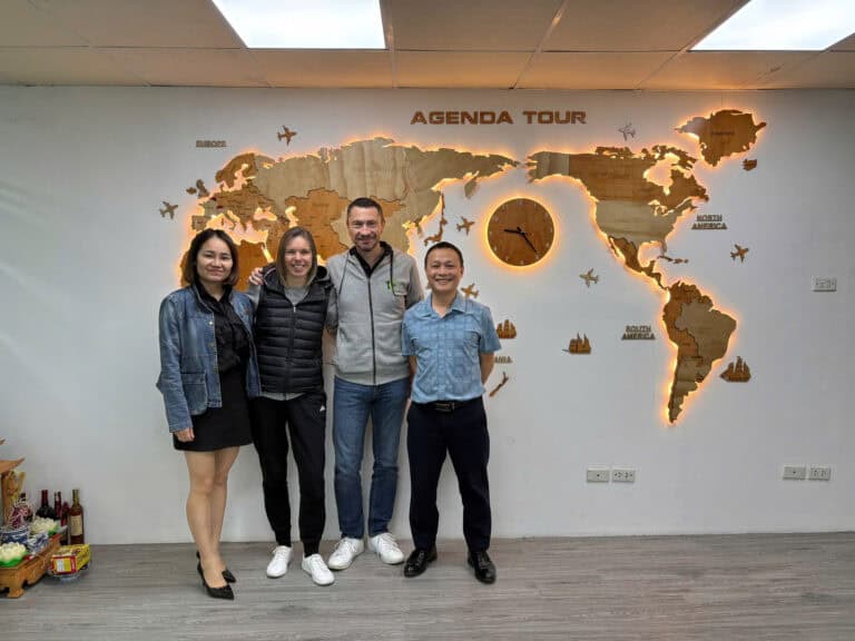 Photo de l'équipe d'Agenda Tour Vietnam devant une carte du monde lumineuse.