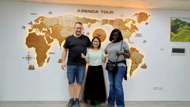 Photo de touristes devant une carte du monde à l'agence Agenda Tour Vietnam.