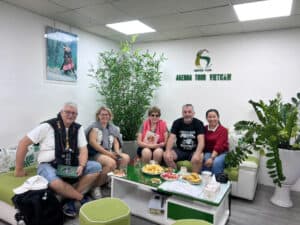 Voyageurs dans un bureau Vietnam, ambiance conviviale, avec plantes vertes et logo Agenda Tour Vietn.