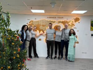 Photo d'une équipe souriante devant une carte du monde à l'agence Agenda Tour Vietnam.
