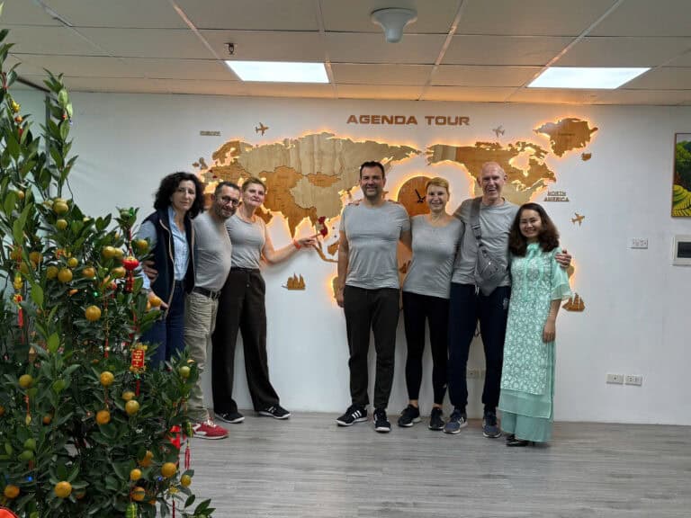 Équipe Agenda Tour Vietnam devant un mur avec une carte du monde.