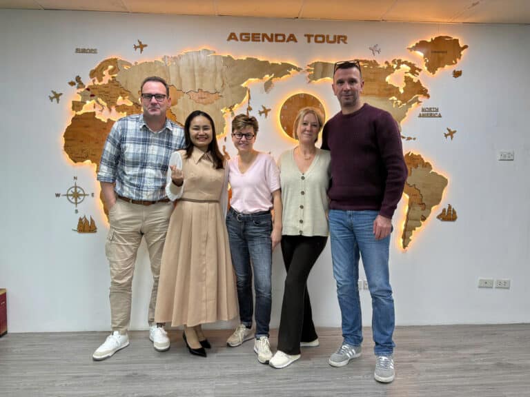 Voyage en groupe avec Agenda Tour Vietnam, devant une carte du monde murale.