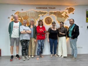 Photo de groupe devant la carte du monde et le logo Agenda Tour Vietnam.