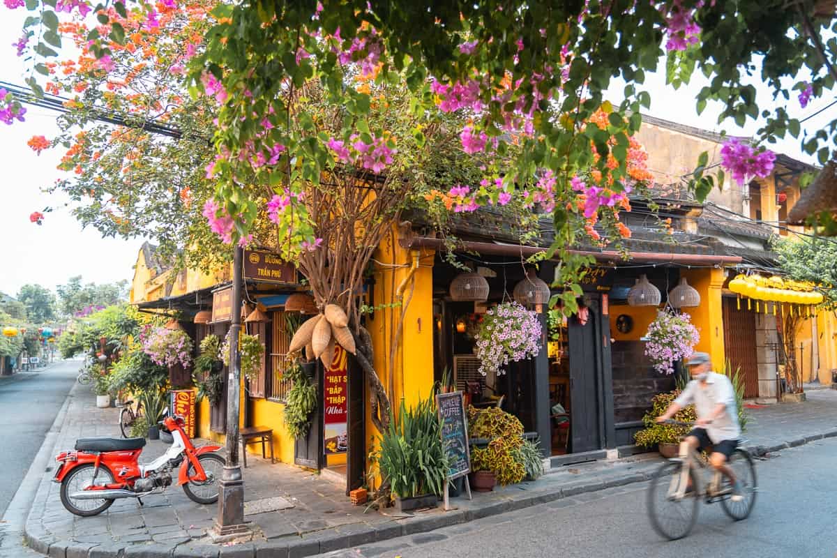 Rue colorée au Vietnam avec un café et des cyclistes.